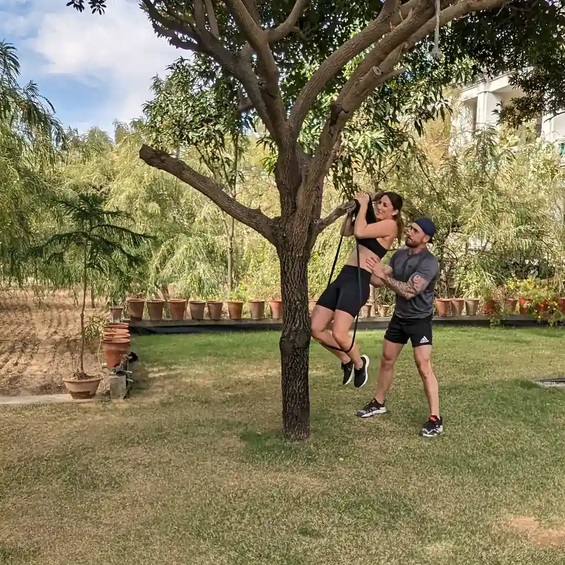 Two guests doing strength training under a tree on the farm
