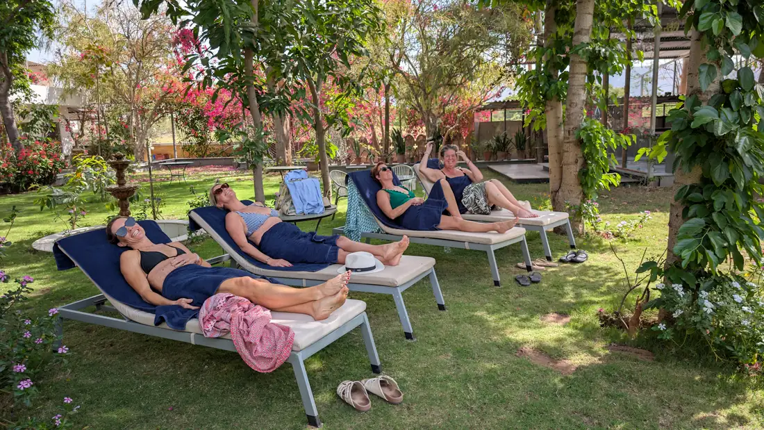 Four retreat guests resting on garden loungers beneath the trees