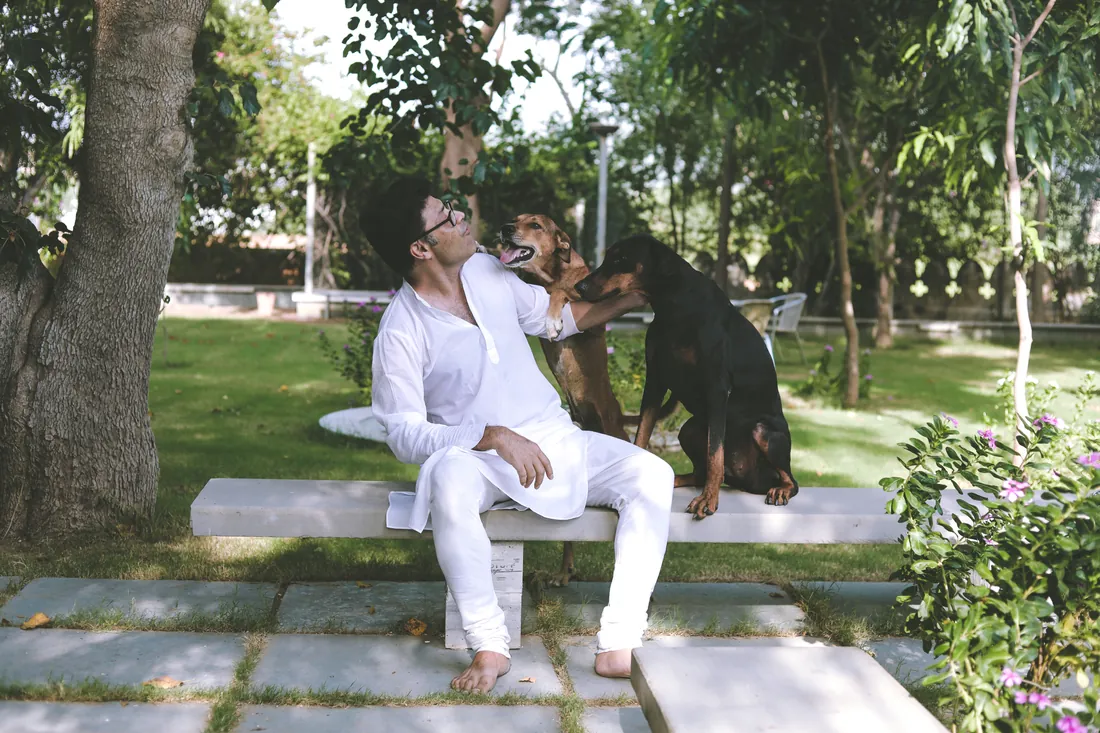 Udai sitting on a garden bench with two farm dogs