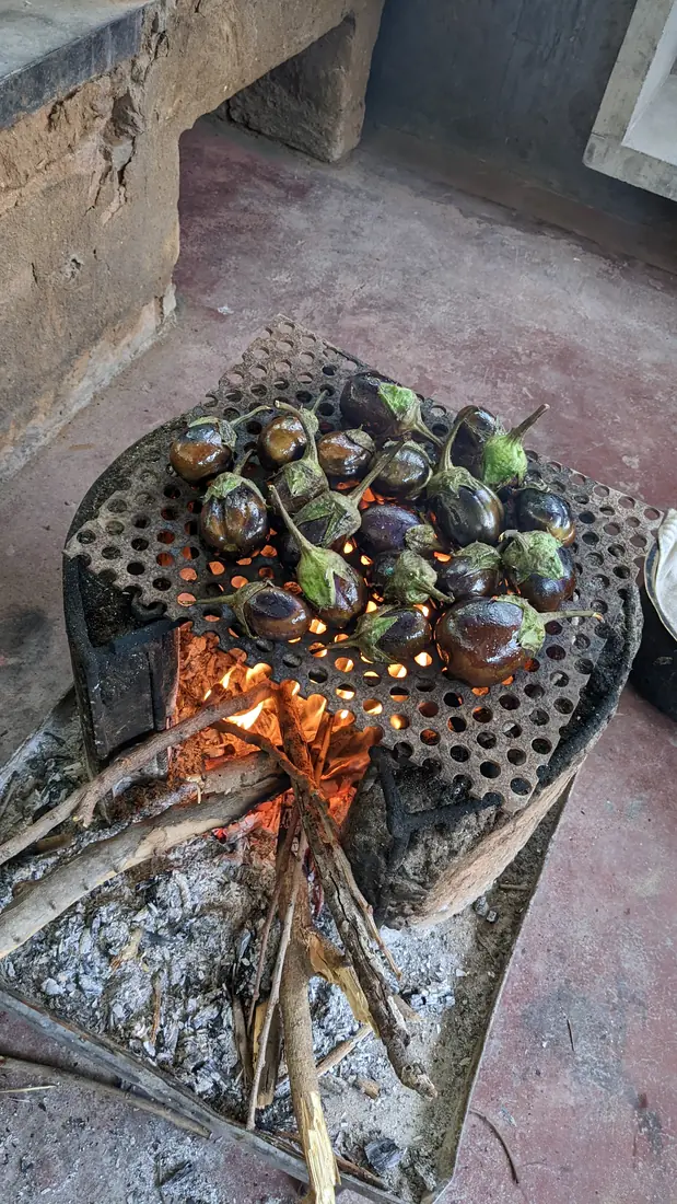 Brinjals roasting over a wood-fired chulha