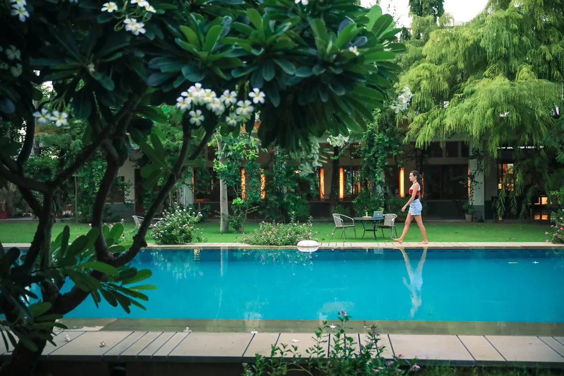 A guest walking along the pool at dusk