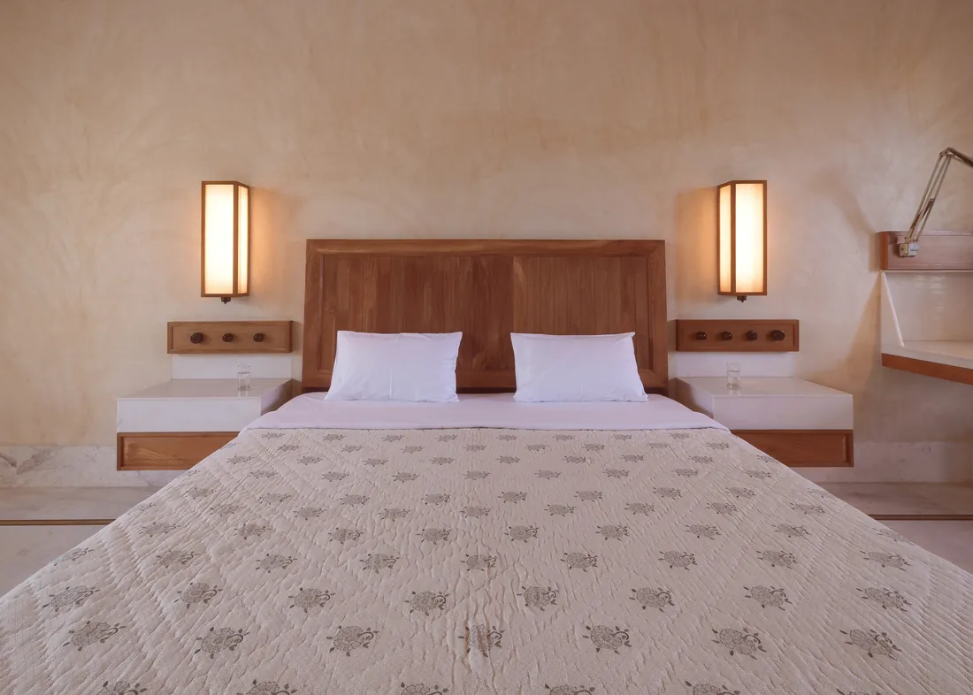 The Deluxe bed, teak headboard, and wall lights