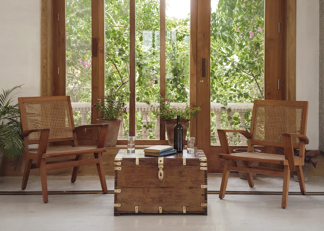 Cane chairs on a veranda facing bougainvillea through open wooden doors