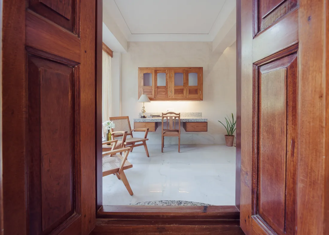 Desk and cane chairs seen through open wooden doors